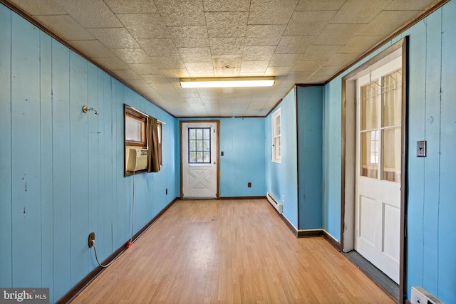 spare room featuring cooling unit, wood walls, hardwood / wood-style floors, and a baseboard radiator