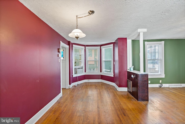 unfurnished dining area with cooling unit, hardwood / wood-style floors, and a textured ceiling