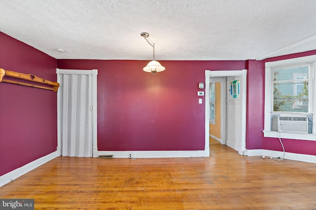 spare room with a textured ceiling, cooling unit, and hardwood / wood-style flooring