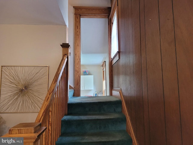 stairway featuring wooden walls