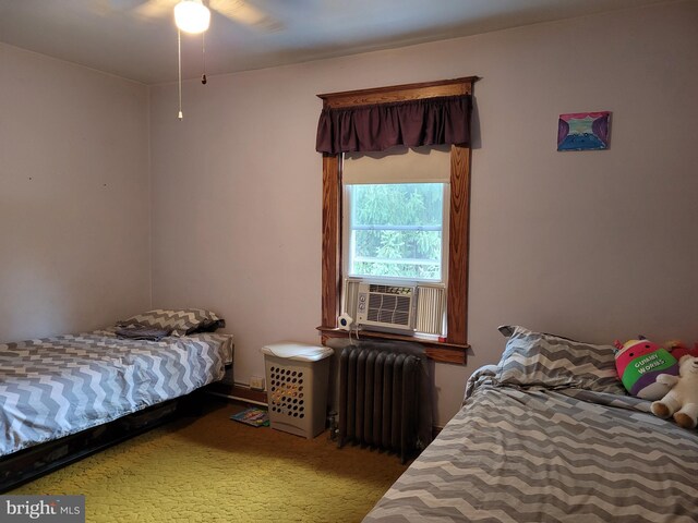 carpeted bedroom with cooling unit, radiator heating unit, and ceiling fan