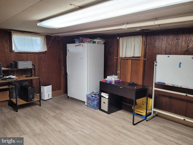 office with light hardwood / wood-style flooring and wood walls