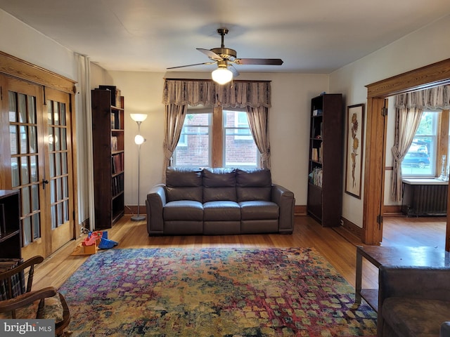 living room with ceiling fan, light wood-type flooring, and a wealth of natural light