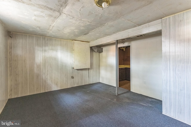 empty room featuring dark carpet and wooden walls