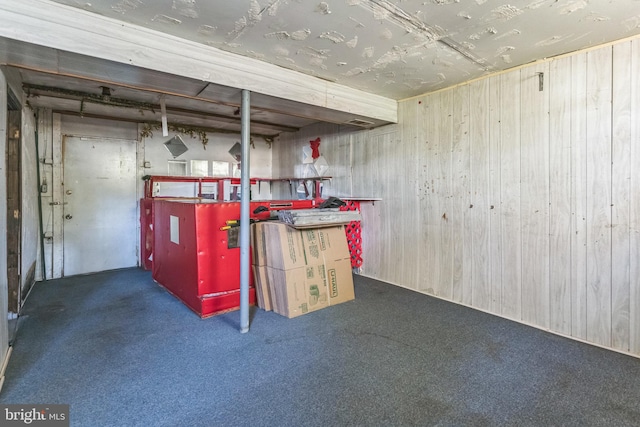 basement featuring dark colored carpet and wood walls