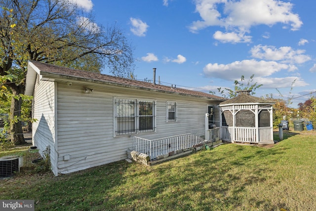 rear view of house with a yard, a gazebo, and central air condition unit