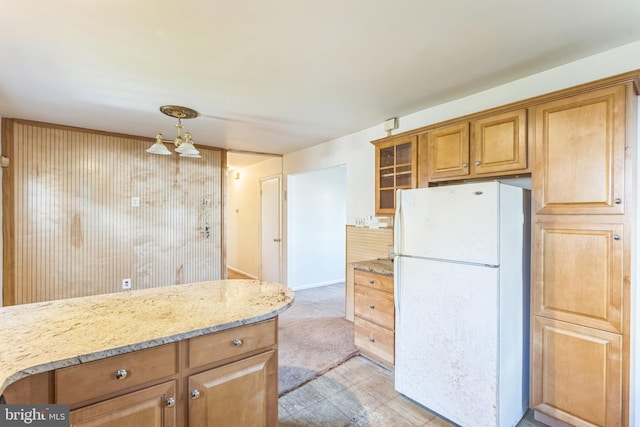 kitchen featuring light stone countertops, white fridge, and decorative light fixtures