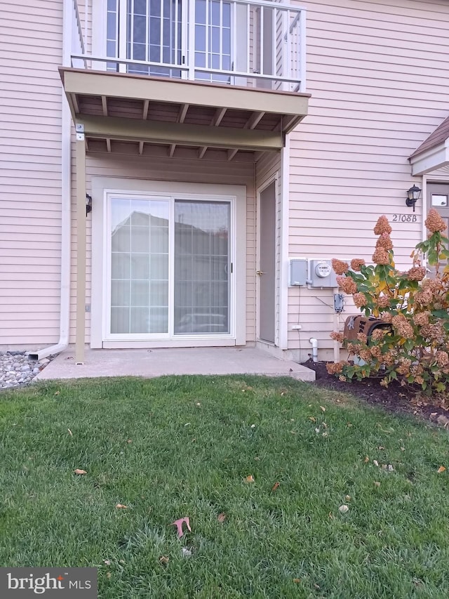 property entrance featuring a lawn and a balcony