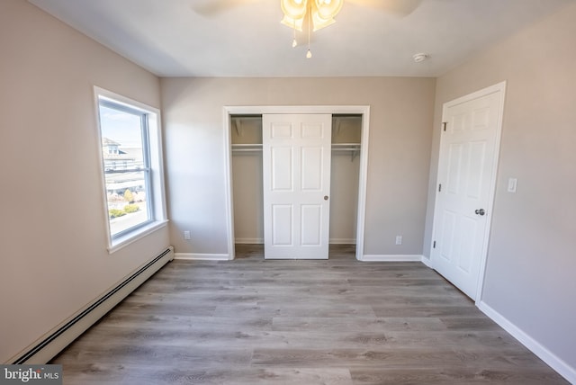 unfurnished bedroom with a closet, ceiling fan, light wood-type flooring, and baseboard heating