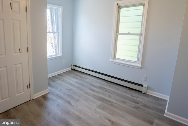 empty room with a baseboard heating unit and light hardwood / wood-style flooring