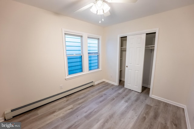 unfurnished bedroom featuring light hardwood / wood-style floors, a closet, baseboard heating, and ceiling fan