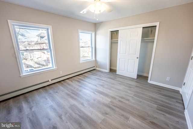 unfurnished bedroom featuring a baseboard radiator, a closet, light wood-type flooring, and ceiling fan