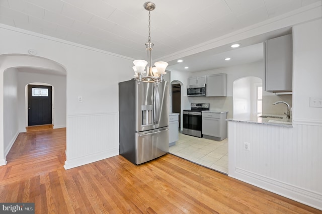 kitchen featuring gray cabinetry, sink, light wood-type flooring, stainless steel appliances, and a notable chandelier