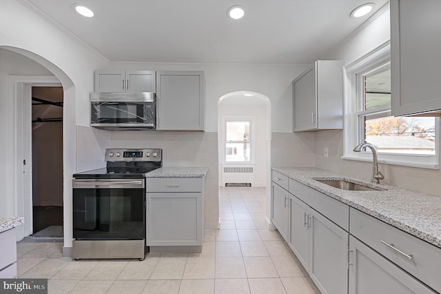 kitchen featuring light tile patterned floors, radiator, sink, gray cabinets, and stainless steel appliances