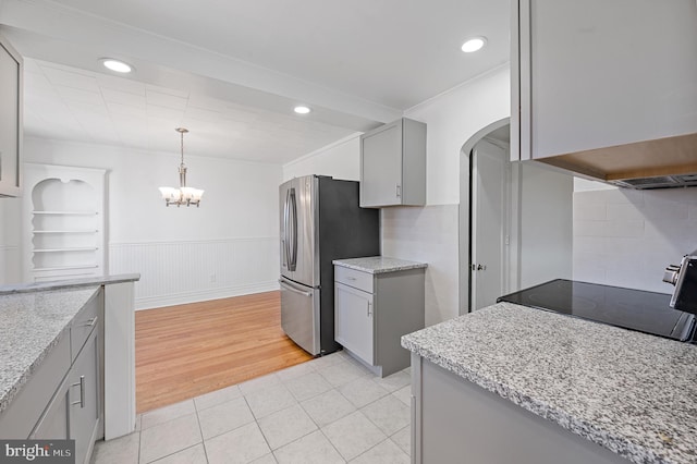 kitchen featuring stainless steel fridge, tasteful backsplash, hanging light fixtures, light hardwood / wood-style flooring, and gray cabinetry