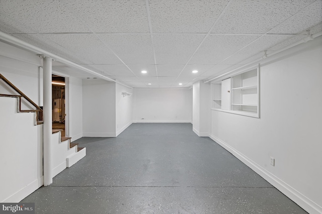 basement with a drop ceiling and built in shelves