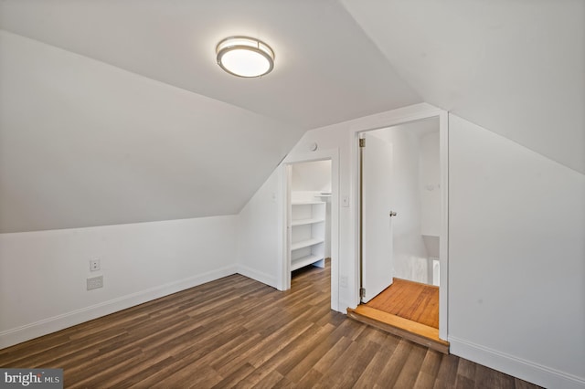 bonus room with dark wood-type flooring and vaulted ceiling