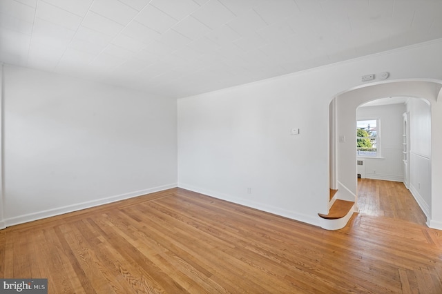 empty room featuring ornamental molding and light hardwood / wood-style flooring