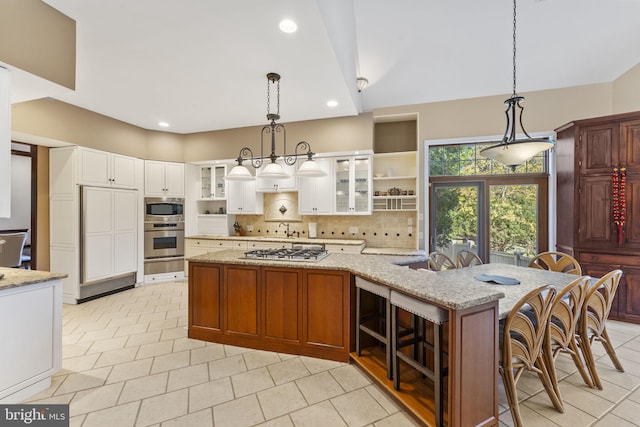 kitchen featuring tasteful backsplash, a kitchen breakfast bar, hanging light fixtures, stainless steel appliances, and light stone counters