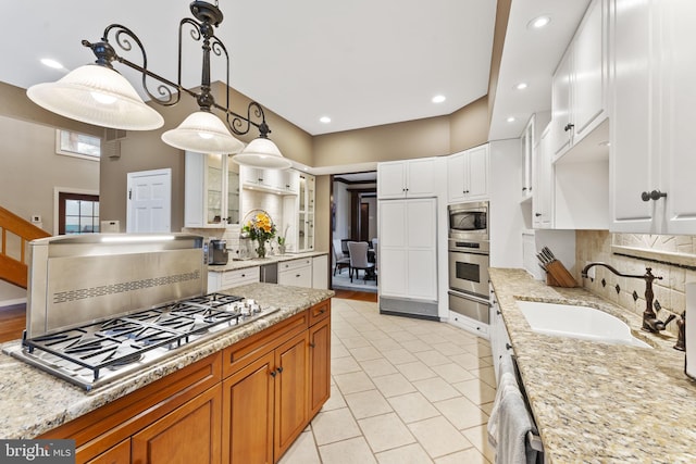 kitchen featuring hanging light fixtures, stainless steel appliances, sink, white cabinetry, and tasteful backsplash