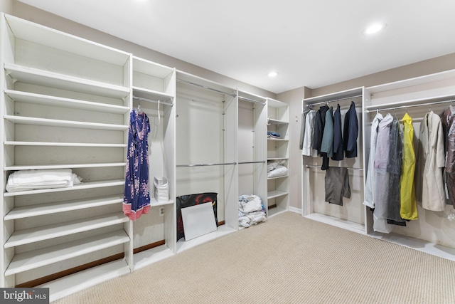 walk in closet with light carpet