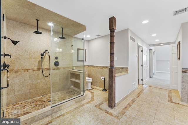 bathroom featuring toilet, tile patterned floors, tile walls, and an enclosed shower