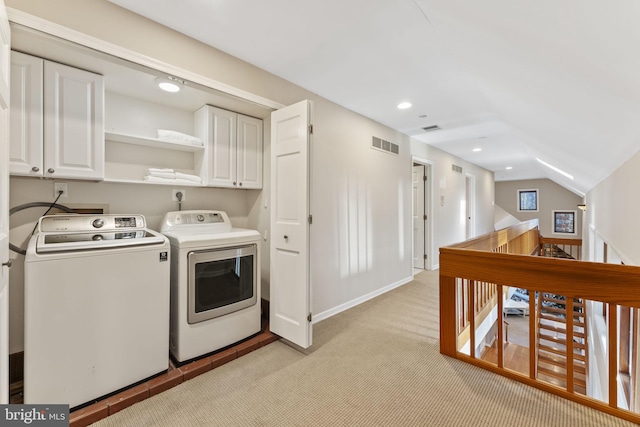 laundry room with washing machine and dryer, light colored carpet, and cabinets