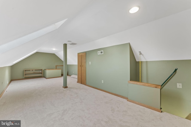 bonus room with lofted ceiling with skylight and light colored carpet