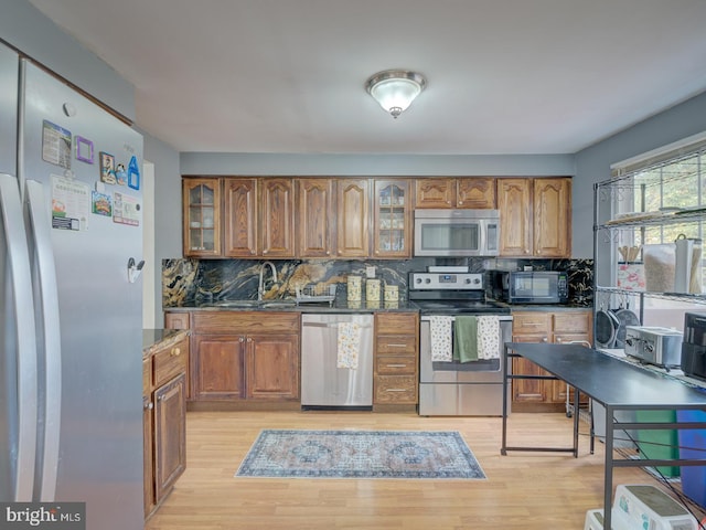 kitchen featuring a sink, light wood finished floors, stainless steel appliances, and brown cabinets