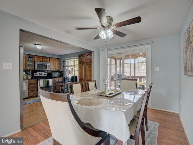 dining space with light wood-style floors, a ceiling fan, and baseboards