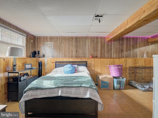 bedroom with wooden walls, tile patterned floors, and a drop ceiling