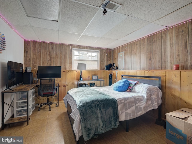 bedroom featuring wooden walls, tile patterned floors, visible vents, and a paneled ceiling
