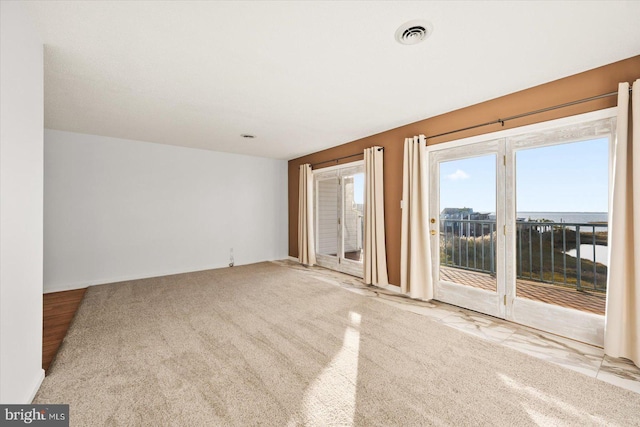 spare room with light carpet and a water view