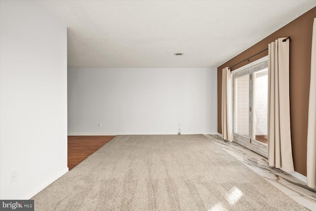 spare room featuring a textured ceiling and light hardwood / wood-style floors