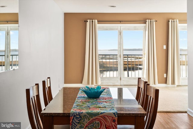 dining area with light hardwood / wood-style flooring and a water view