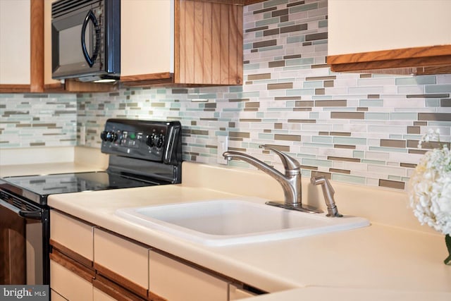 kitchen with decorative backsplash, black appliances, and sink