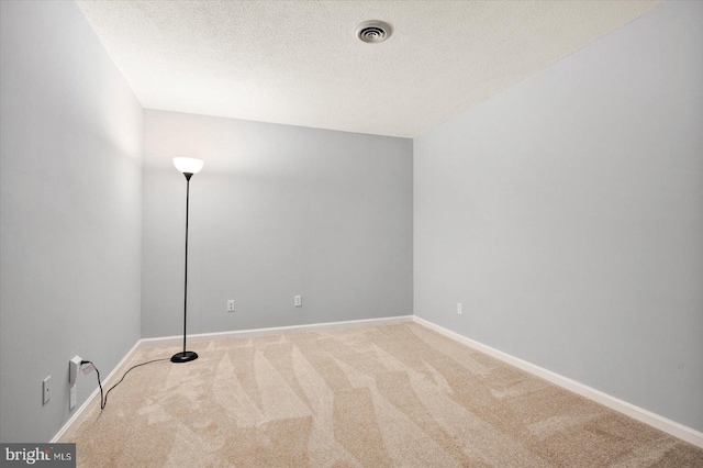 carpeted empty room featuring a textured ceiling