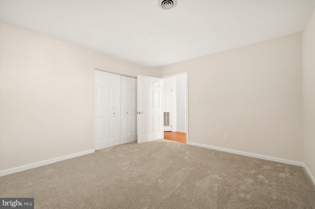 unfurnished bedroom featuring a closet and light colored carpet