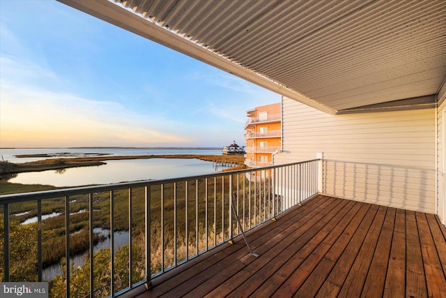 balcony at dusk featuring a water view