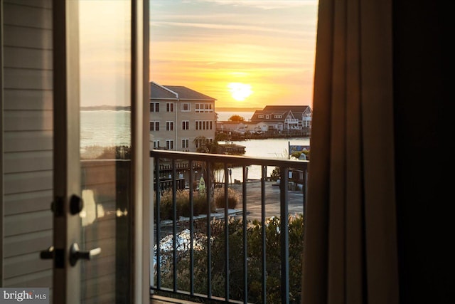 balcony at dusk featuring a water view