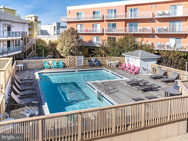 view of swimming pool featuring a storage unit and a deck