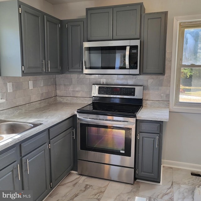 kitchen featuring decorative backsplash, stainless steel appliances, and gray cabinets