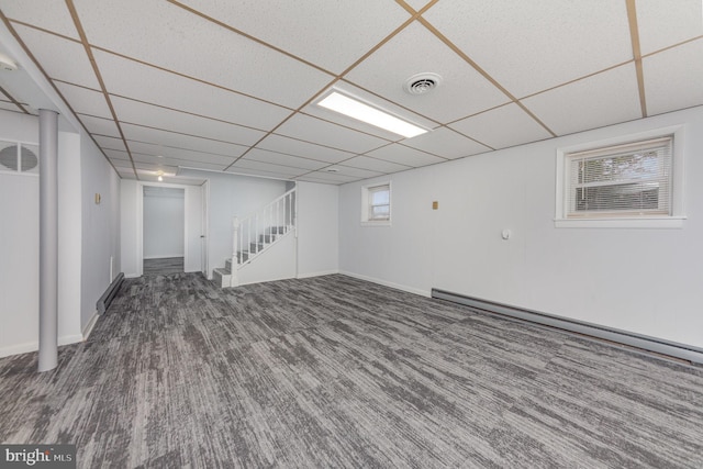 basement with a paneled ceiling, wood-type flooring, and a baseboard heating unit