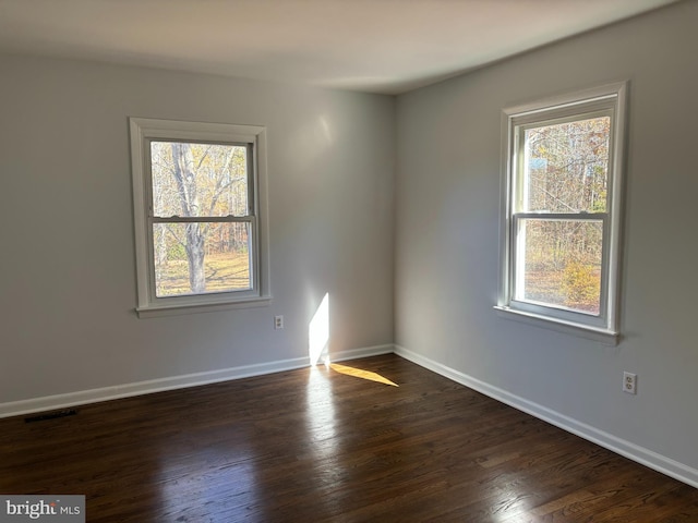 unfurnished room featuring dark hardwood / wood-style floors and plenty of natural light