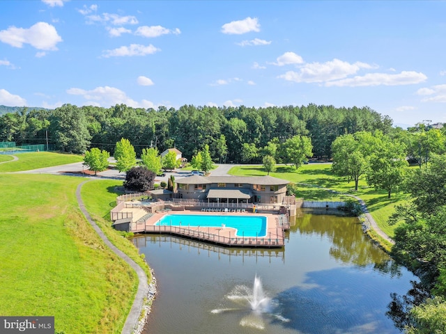 exterior space featuring a patio area, a pool, a water view, and a lawn