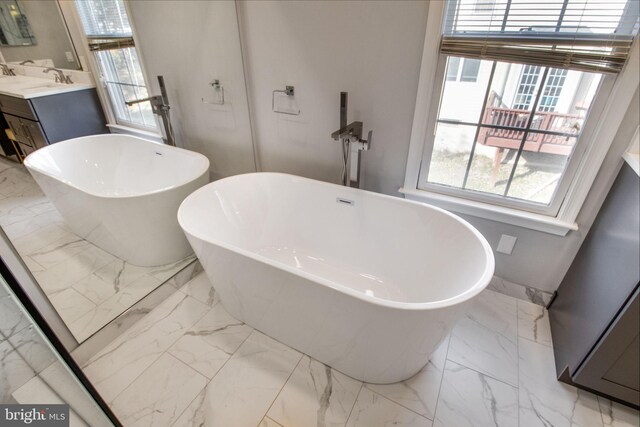 bathroom with washer / clothes dryer, a tub to relax in, and vanity