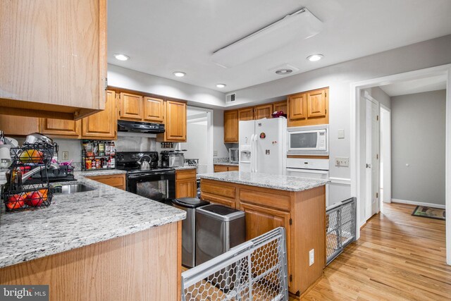 kitchen with sink, tasteful backsplash, light stone countertops, white appliances, and light hardwood / wood-style flooring