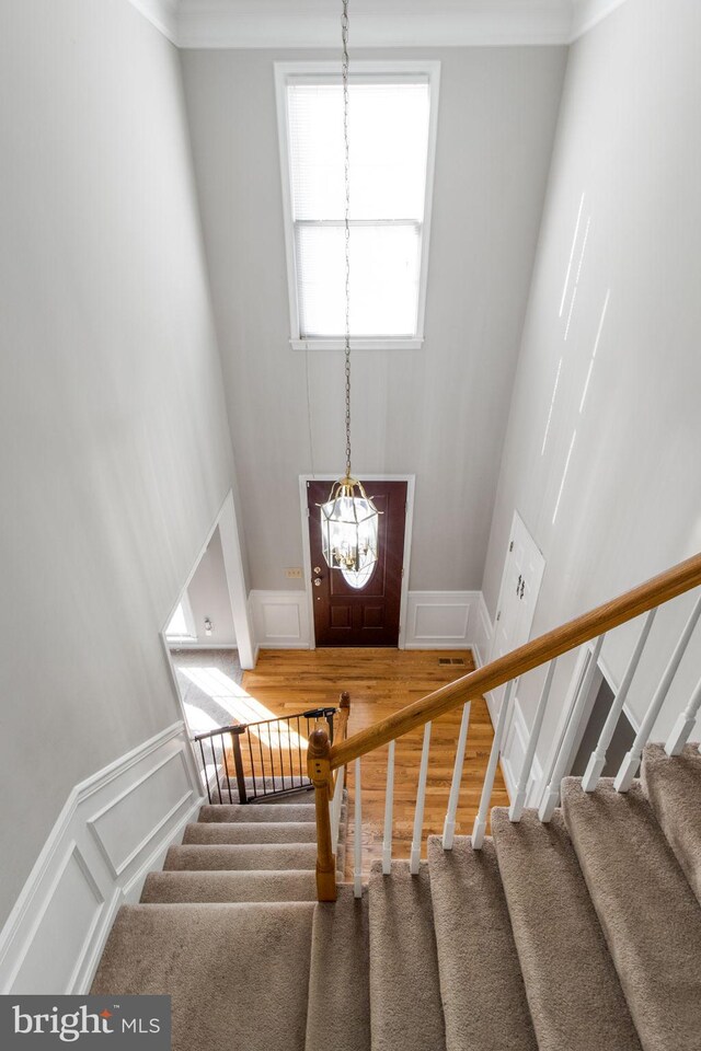 stairs with a chandelier, hardwood / wood-style flooring, and a towering ceiling