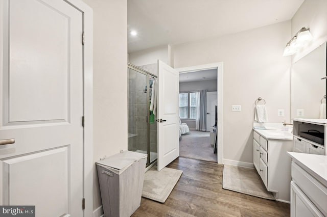 bathroom with hardwood / wood-style floors, a shower with door, and vanity