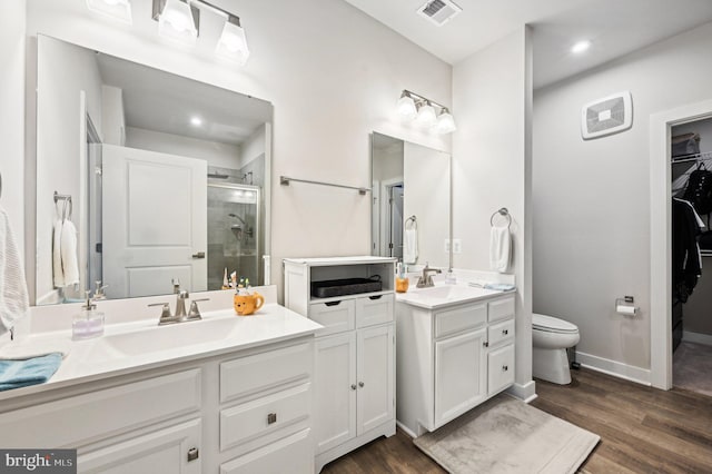 bathroom featuring walk in shower, wood-type flooring, vanity, and toilet